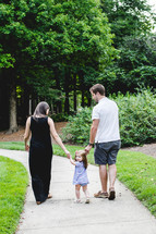 a family walking down a path holding hands 