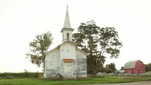 a rural white church and red barn 