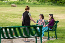 Woman sharing a gospel tract with people on a park bench