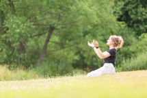 Woman worshipping God in grassy field