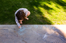 a girl coloring with sidewalk chalk 
