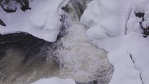 Aerial drone shot of a frozen waterfall nestled in a wintry forest landscape