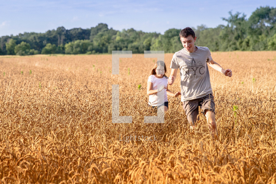 children running in a field of wheat 