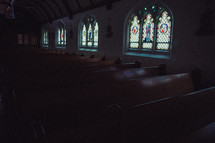 rows of empty pews in a dark church 