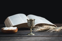 Small chalice and wafers for communion next to a Bible