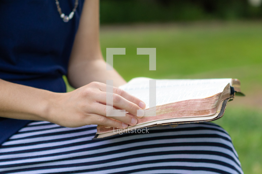 Christian woman sitting outside having quiet time and reading Bible 
