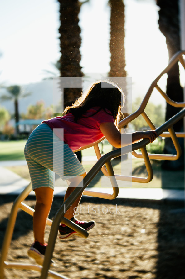 a little girl climbing up playground equipment 