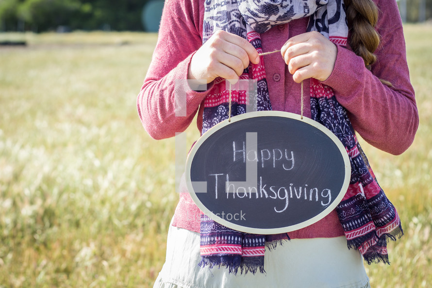 a girl holding a sign with the words Happy Thanksgiving 