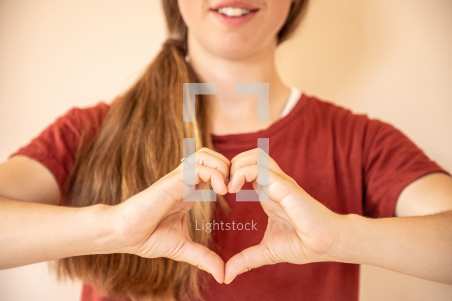 a girl making a heart shape with her hands 