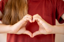 a girl making a heart shape with her hands 