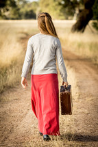 Girl with Suitcase Walking down road