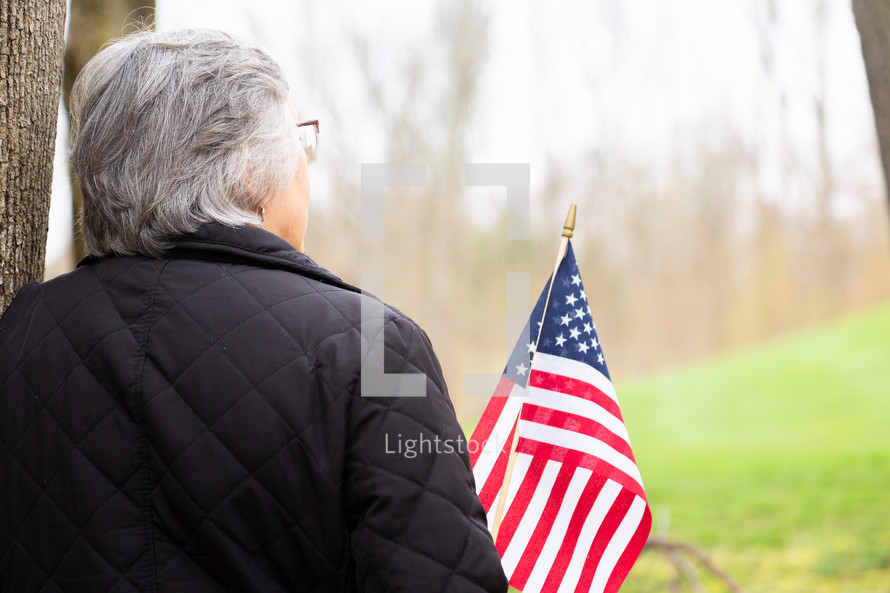 Woman in deep thought holding American flag