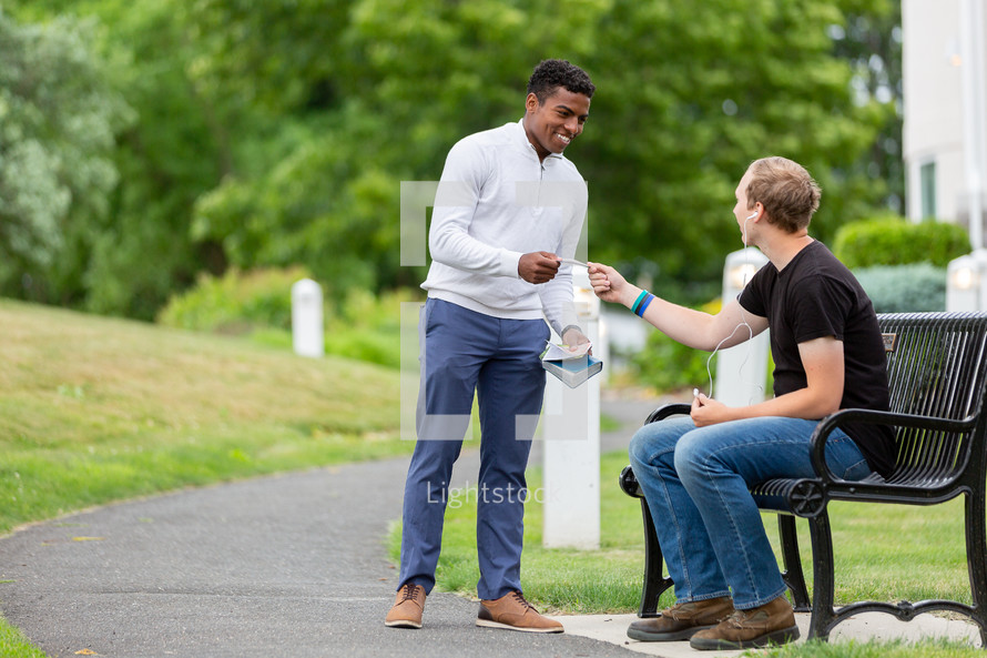 Man handing out a tract in a park