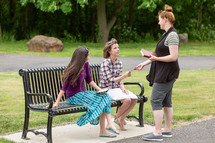 Woman sharing a gospel tract with people on a bench