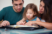 Family Studying Bible With Child 
