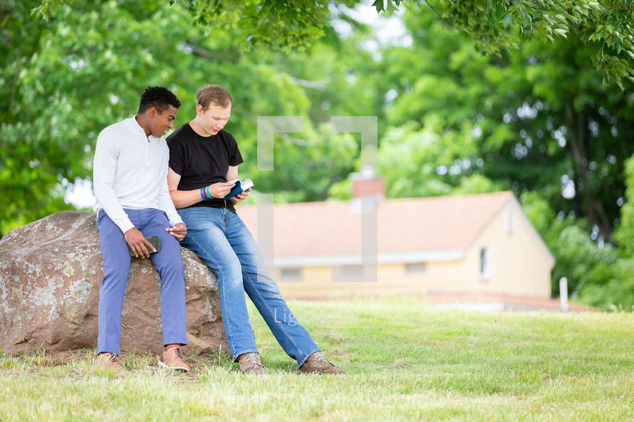 Two men outdoors reading the Bible