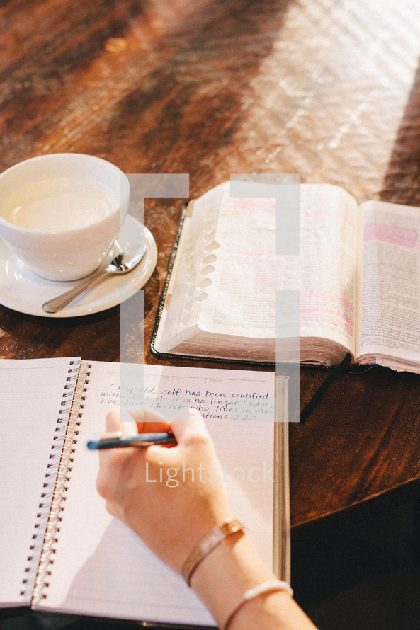 a woman writing in a notebook in a coffee shop at a Bible study 