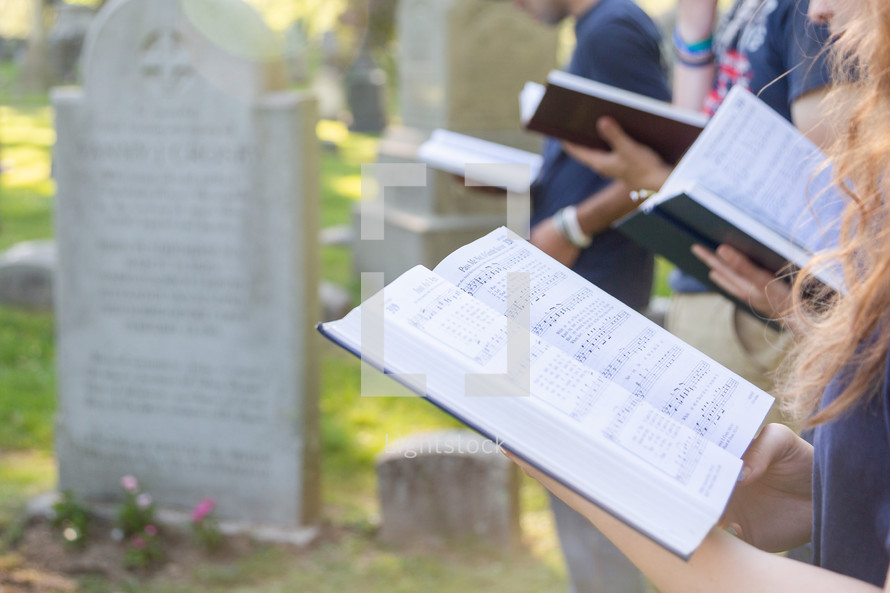 Singing from a hymnal at cemetery