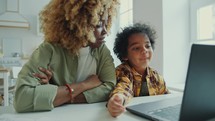 Interested Little Boy Watching Video on Laptop with Mother at Home
