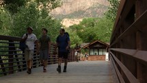 men with backpacks walking across a bridge 