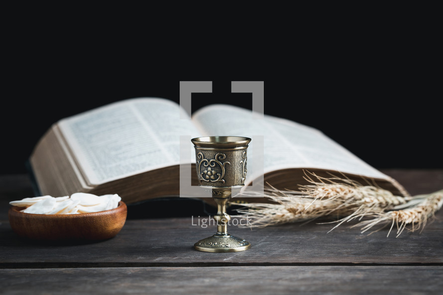 Small chalice and wafers for communion next to a Bible