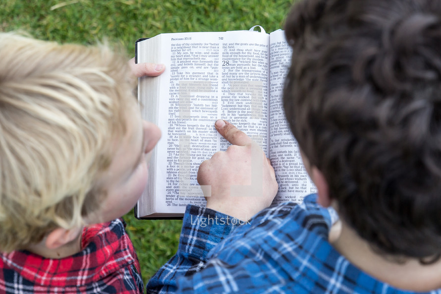 a father reading a Bible to his son 