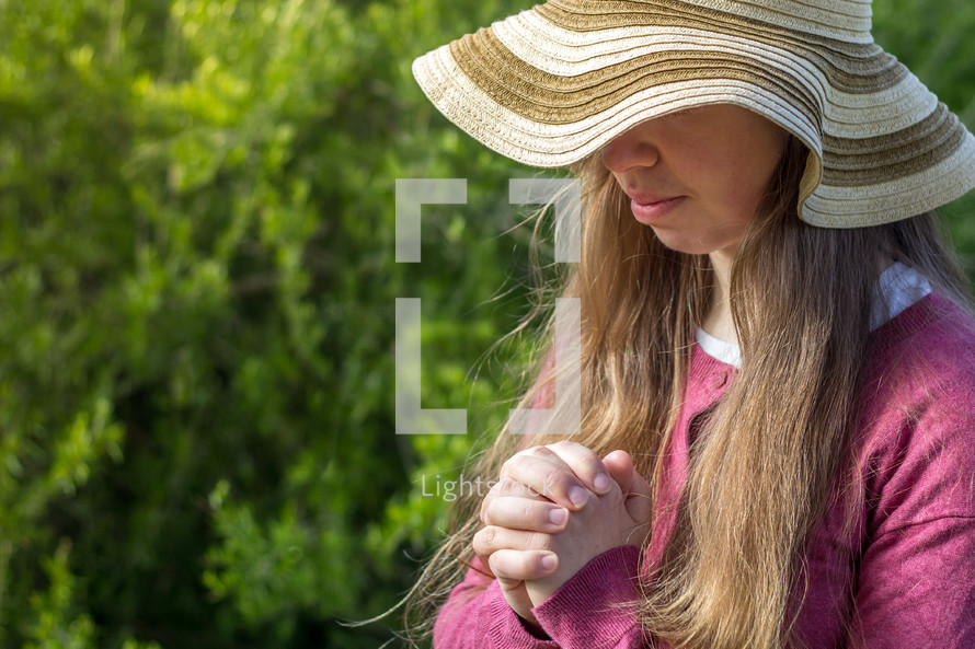 praying girl in a straw hat 