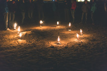 People standing around a circle of burning torches at night.