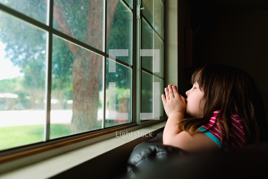 a girl praying in a window 