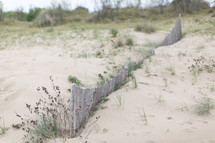 A wooden fence on a sandy beach.