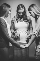 Mother and daughters holding hands and praying.