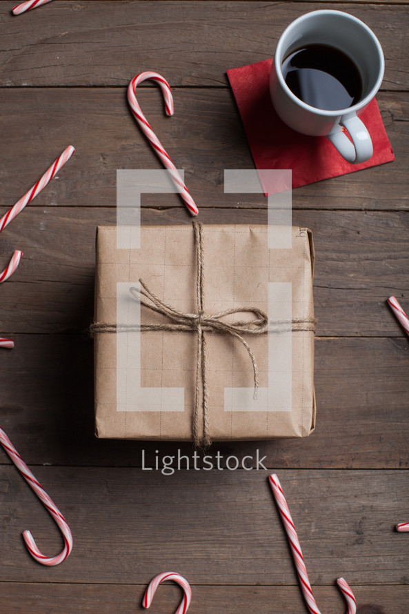 wrapped gift, candy canes, wood floor, brown paper, coffee, mug, red napkin, wood table, Christmas 