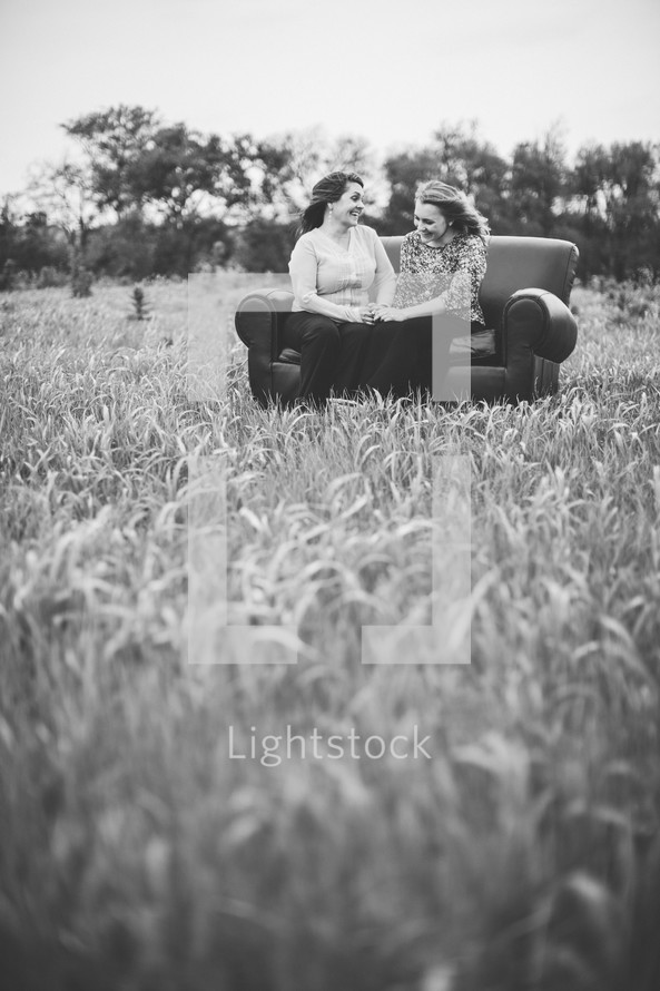 mother and daughter in conversation sitting on a couch outdoors in a field