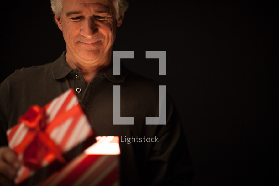 A man looks into a box - An illuminated gift - the gift of salvation through Jesus Christ 