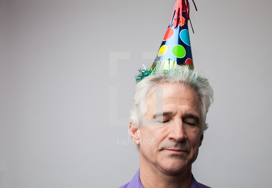 man with closed eyes wearing a party hat 