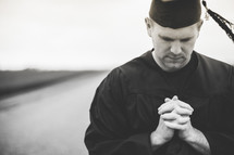 Graduate praying in the middle of the road.