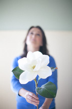 woman holding a magnolia flower looking up to God