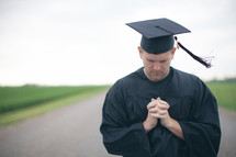 Graduate praying in the road.