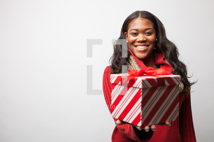 Joyful woman presenting a Christmas gift.