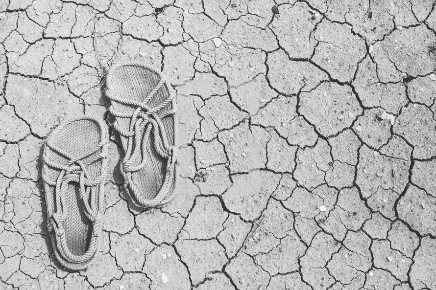 Rope sandals on the dry, cracked earth.