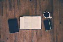 journal, coffee mug, open Bible, and book on a wood floor 