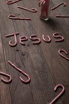 word Jesus out of candy canes on a wood floor 