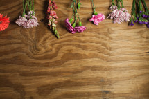 Drying flowers laying on a panel of wood.