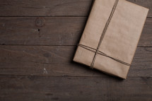 gift wrapped in brown paper on a wood floor 