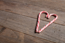 candy canes in the shape of a heart on a wood floor 