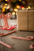 wrapped gift and candy canes spread out on a wood floor 