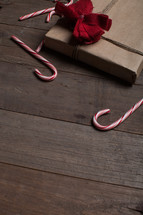 candy canes and wrapped gift on a wood floor 