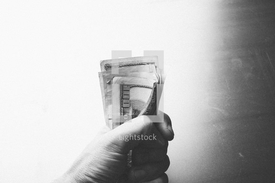 Fist grasping stack of paper money.