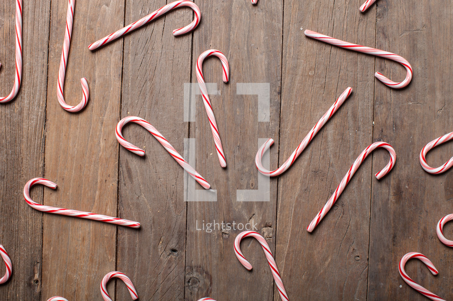candy canes spread out on a wood floor 