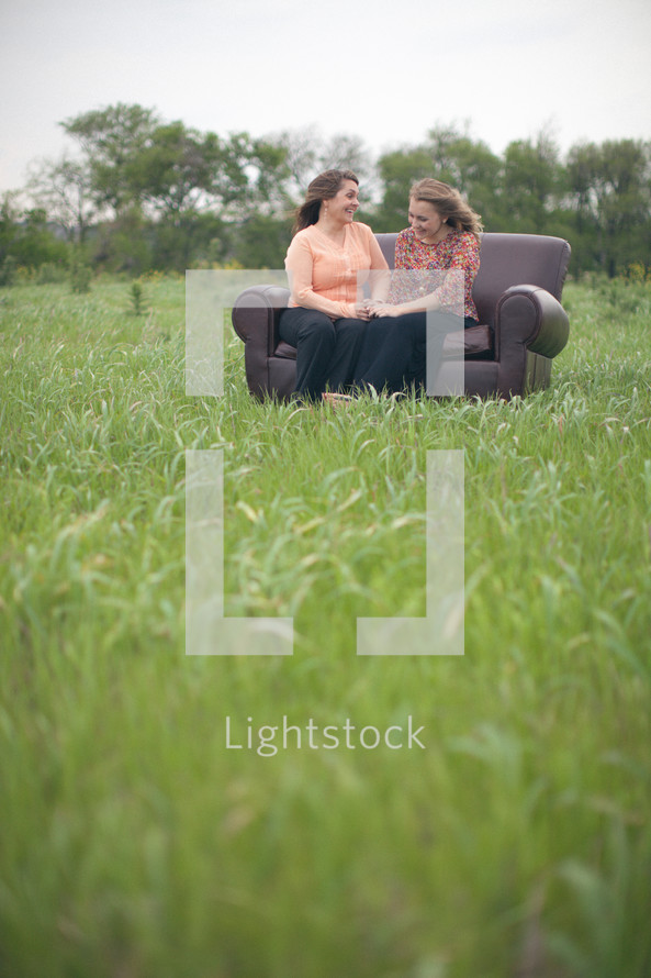 mother and daughter sitting on a couch talking together outdoors 